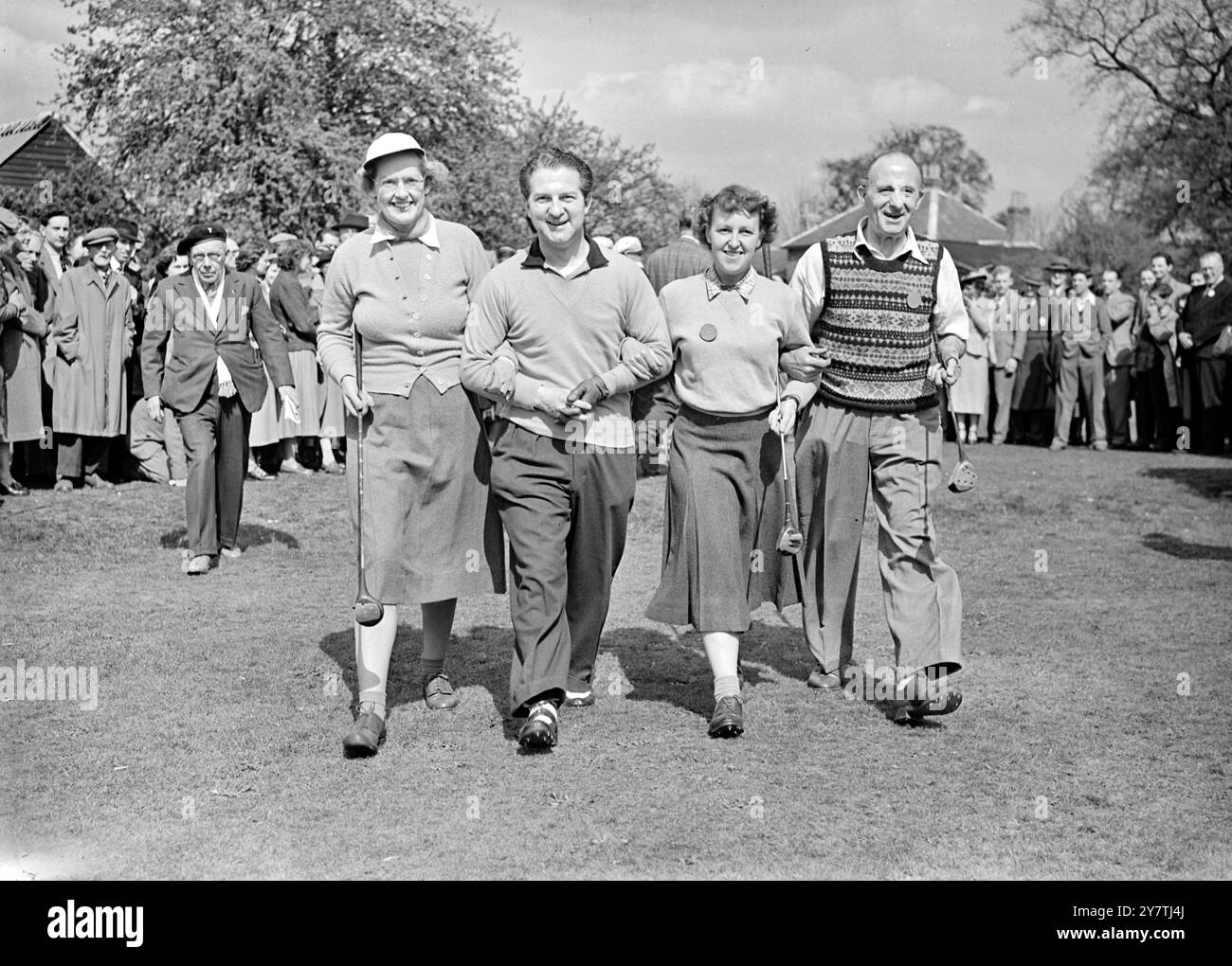 Hampton Hill , Middlesex : le chanteur Donald Peers relie les armes à ses adversaires Mme R Sutherland Pilch (à gauche) et Mlle Nancy Jupp, alors qu'ils marchent joyeusement autour du parcours du Fulwell Golf Club pendant les quatuors de quatre balles entre une équipe féminine représentative et la Vaudeville Golf Society. À droite, Jack Hodges, partenaire de Donald, le .23 avril 1950 Banque D'Images