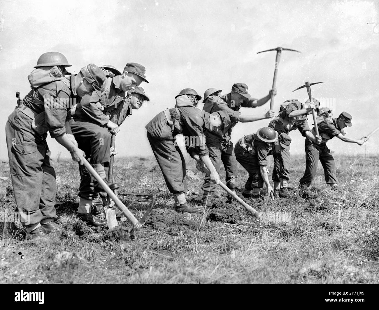 Tests de l'armée nouveau dressWarminster , Wiltshire : la tenue de combat projetée pour l'armée britannique a été soumise à des tests rigoureux par les hommes du 1er Bataillon Lancashaire fusiliers sur la chaîne Imber près d'ici. L'objet de l'exercice était de tester les propriétés de dissipation de la chaleur et de la sueur du nouvel outft. Photo montre : portant la nouvelle combinaison de combat , les hommes des Fusiliers du Lancashire ' creusent ' après avoir attaqué une position. Après l'exercice , les hommes ont été pesés , la température et le pouls ont été enregistrés . La sueur contect de l'uniforme a également été mesurée. 16 août 1949 Banque D'Images