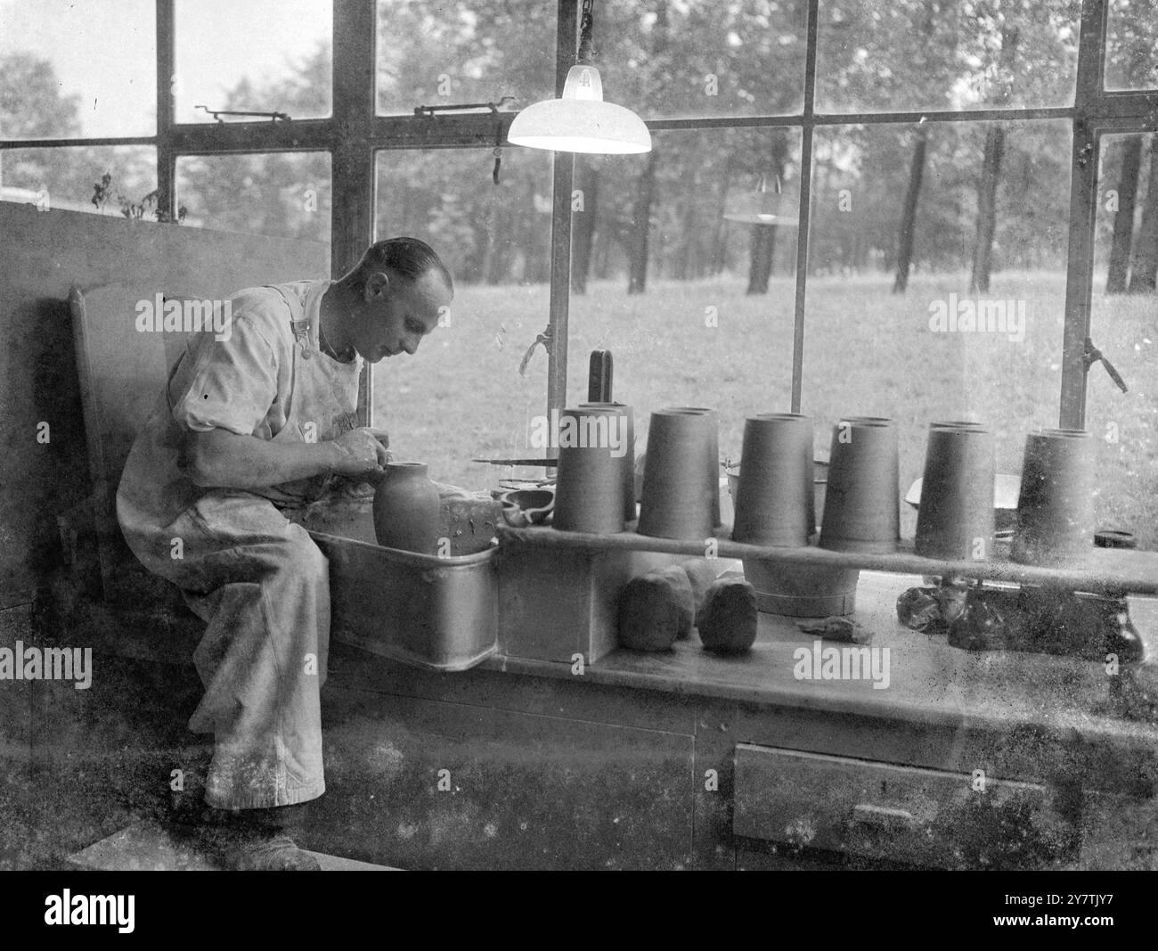 Artisanat du potier - Stoke-on-trent , Staffordshire : Fred Simpson , 41 , un lanceur à la poterie Josiah Wdgewood est assis à cheval sur un banc tout en travaillant sur un vase - août 1949 Banque D'Images