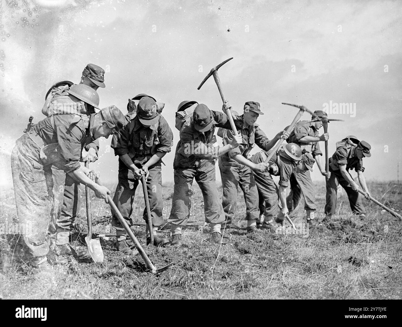 Tests de l'armée nouveau dressWarminster , Wiltshire : la tenue de combat projetée pour l'armée britannique a été soumise à des tests rigoureux par les hommes du 1er Bataillon Lancashaire fusiliers sur la chaîne Imber près d'ici. L'objet de l'exercice était de tester les propriétés de dissipation de la chaleur et de la sueur du nouvel outft. Photo montre : portant la nouvelle combinaison de combat , les hommes des Fusiliers du Lancashire ' creusent ' après avoir attaqué une position. Après l'exercice , les hommes ont été pesés , la température et le pouls ont été enregistrés . La sueur contect de l'uniforme a également été mesurée. 16 août 1949 Banque D'Images