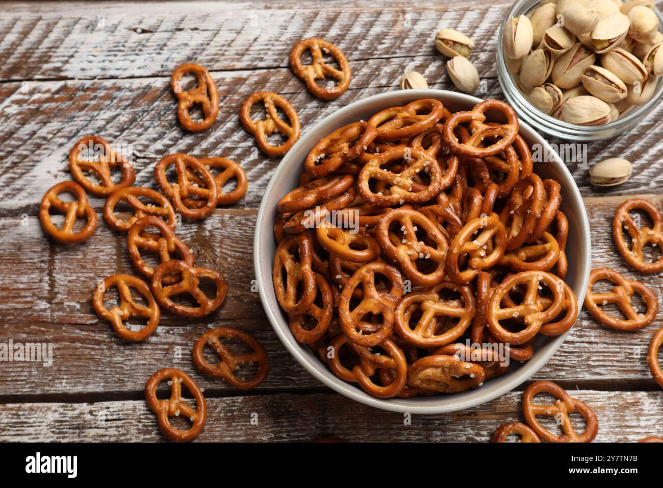 Délicieux craquelins de bretzel salés et pistaches sur table en bois, pose à plat Banque D'Images