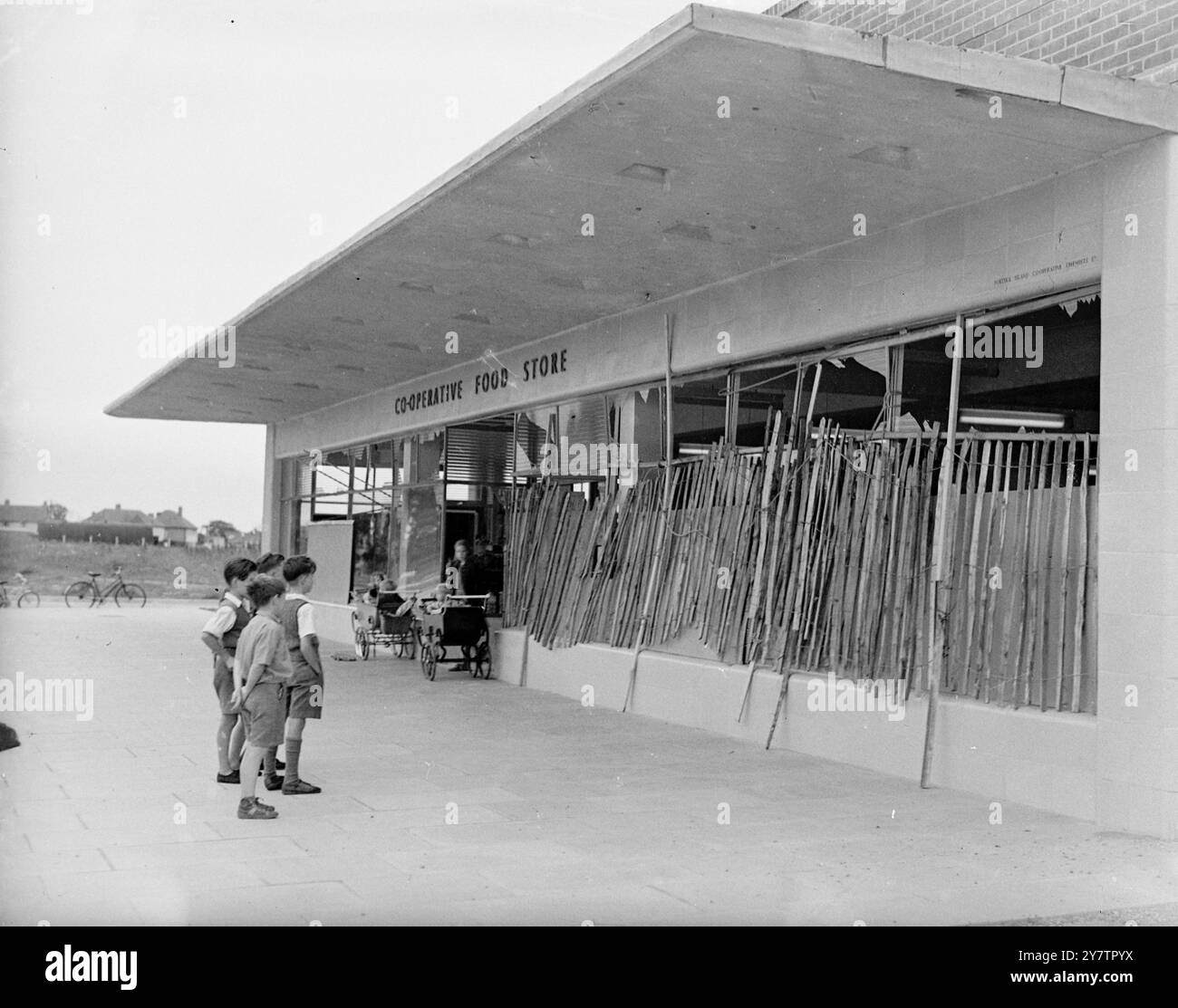PAS UNE VUE INCONNUE - COMME UN AUTRE 'BLITZ' FRAPPE PORTSMOUTH. Des enfants inspectent l'un des résultats de la double explosion qui a secoué cette ville navale de la côte sud récemment lorsque 1400 tonnes d'obus et de bombes ont explosé au dépôt de munitions de la Royal Naval ici. Mais ce n'était pas la première fois que les enfants avaient vu une façade de magasin arborée, car Portsmouth et Gosport voisin (où cette photo a été prise) avaient leur part de bombardements pendant la guerre. Il y avait deux principaux centres d'explosion - sur une chaîne de barges de munitions, dont huit ont été coulées, et l'autre sur une jetée de chargement de munitions, whe Banque D'Images