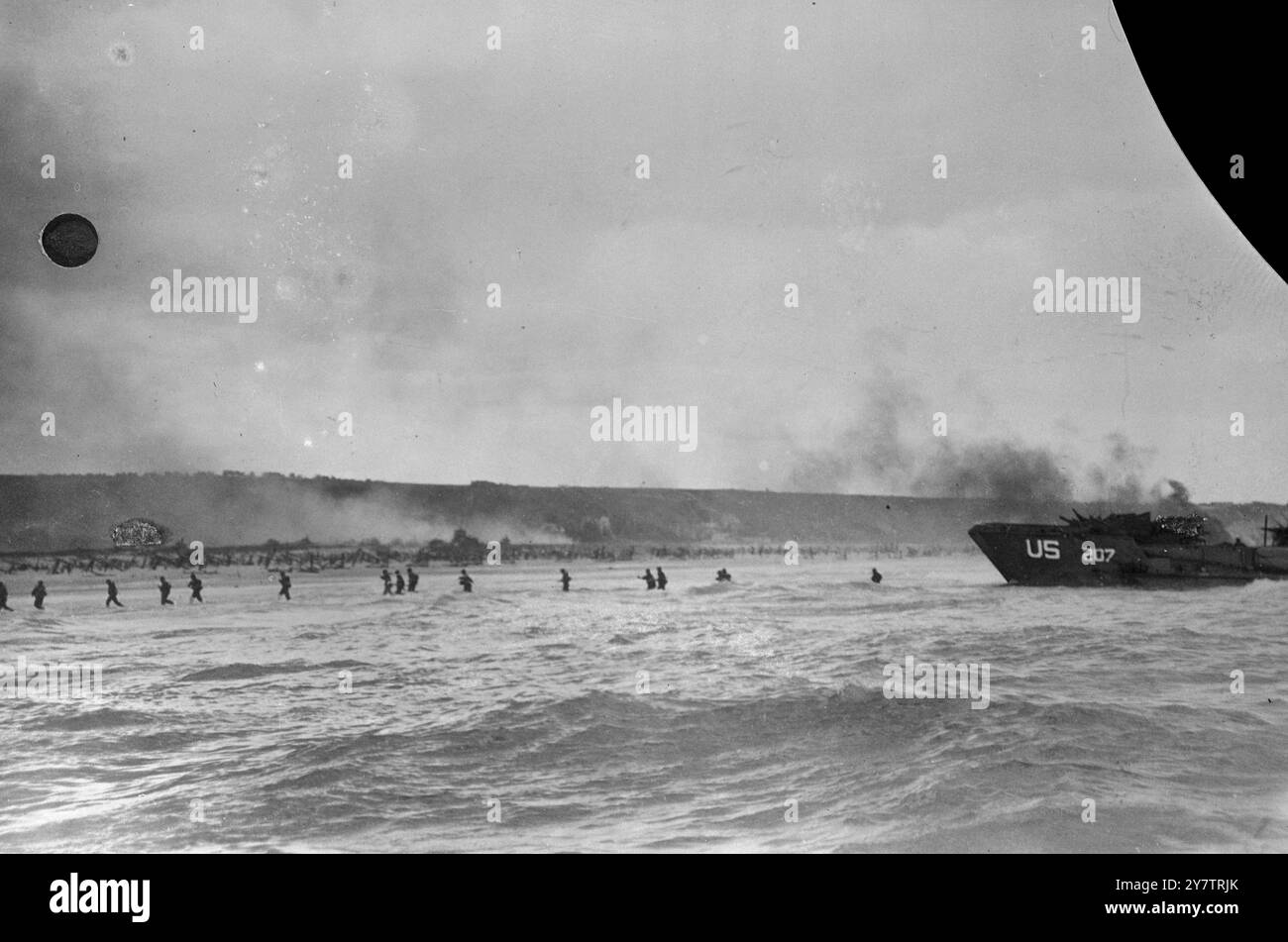 Sous le couvert de tirs d'obus navals qui formaient un écran lorsque les premiers hommes débarquaient - des fantassins américains pataugeaient dans les vagues pour effectuer les premiers débarquements sur le St-Laurent-sur-mer ( Omaha Beach ) - des transports américains sur la droite.6 juin 1944 Banque D'Images