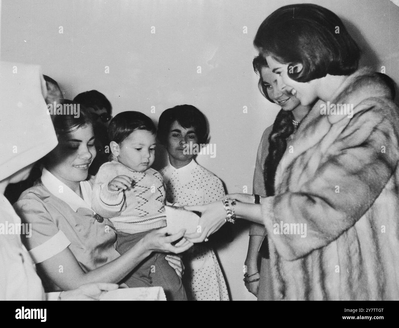 491302 ANNE-MARIE PARMI LES BÉBÉS ATHÈNES : LA REINE ANNE-MARIE DE GRÈCE OFFRE UN MORCEAU DE GÂTEAU À UNE INFIRMIÈRE DU CENTRE POUR BÉBÉS MITERA À ATHÈNES, ALORS QUE LA PRINCESSE DANOISE F0RMER A VISITÉ LE CENTRE, LE 7 JANVIER. EN ARRIÈRE-PLAN SE TROUVE LA PRINCESSE SOPHIE DES ASTURIES, ÉPOUSE DE DON JUAN CARLOS, FILS DU PRÉTENDANT ESPAGNOL. LA REINE ANNE-MARIE, ÉPOUSE DU ROI CONSTANTIN DE GRÈCE, ATTEND SON PREMIER BÉBÉ PLUS TARD CETTE ANNÉE, LE 9 JANVIER 1965 Banque D'Images