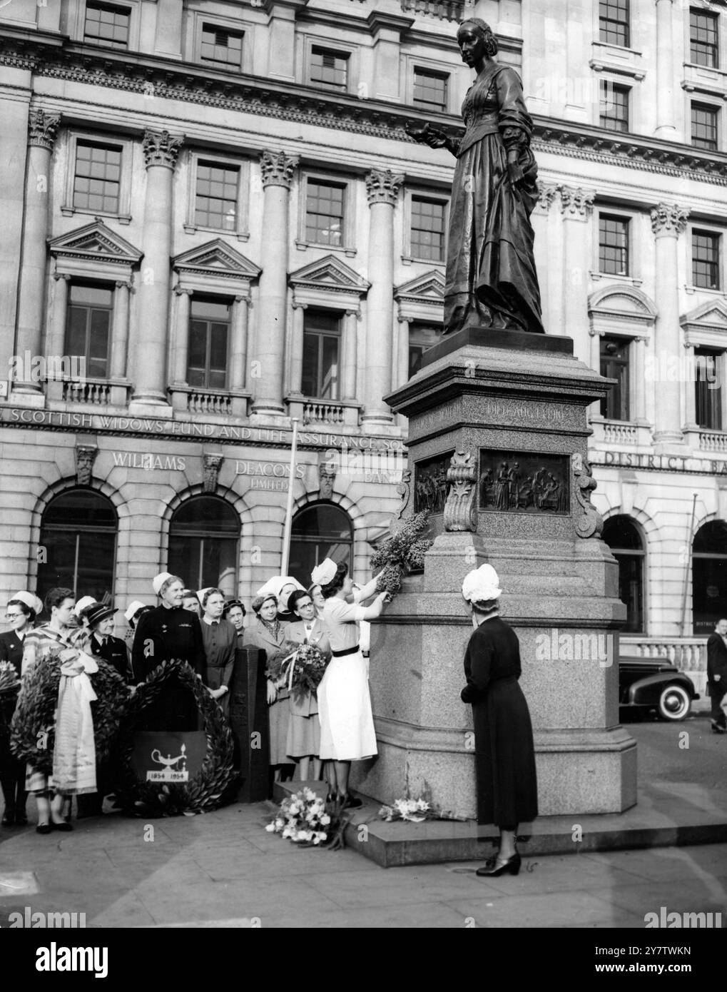 L'infirmière Patricia Daniel, de la Florence Nightingale School, St Thomas' Hospital, Londres, dépose une couronne sur le mémorial Florence Nightingale à Waterloo place, lors d'un service commémoratif tenu à 7h30 aujourd'hui - le 134e anniversaire de la naissance de Mlle Nightingale. D'autres membres de la profession infirmière sont vus en attente de déposer leurs couronnes.12 mai 1954 Banque D'Images