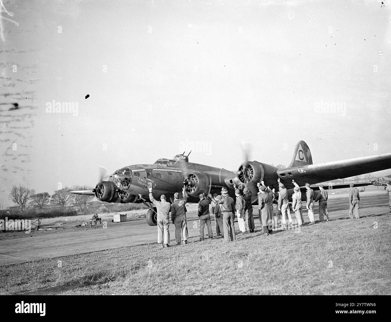 « KNOCK OUT DROPPER » TIENT LA TÊTE DANS LE MARATHON DE BOMBARDEMENT DE FORTERESSE VOLANTE. Photo : alors que la forteresse volante « Knock Out Droppe R » se déplace sur la piste, son équipage au sol qui l'a gardée en vol pendant 49 missions opérationnelles lui donne un coup de fouet. 13 novembre 1943 Banque D'Images