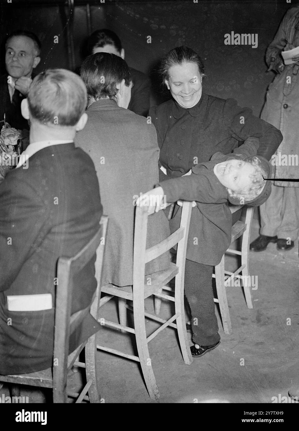 UN ENFANT DE TROIS ANS DIVERTIT LES DÉLÉGUÉES COMMERCIALES SOVIÉTIQUES lors de leur visite des services de la défense civile à Londres les déléguées syndicales soviétiques ont visité un centre de repas londonien (un dépôt d'alimentation communautaire) à Deptford et ont profité d'un déjeuner de tenpenny composé d'une tarte à la viande et de deux légumes, suivi de prunes et de crème anglaise. Shirley Morris, âgée de trois ans et demi, a fait des tours acrobatiques sur des chaises, puis est montée dans les bras de Madame A S Malkova, l'une des déléguées soviétiques. Althoug incapable de parler la même langue l'appel universel des bébés à la femme Banque D'Images