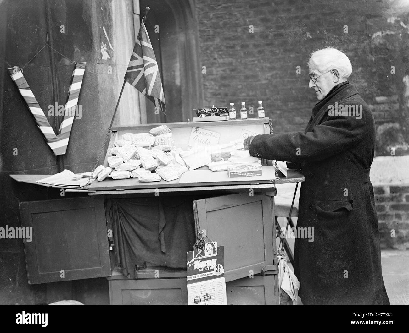 LONDRES EN TEMPS DE GUERRE - PAS DE BONBONS OU DE CIGARETTES - M. David Healy, âgé de 63 ans, est à son étal devant la porte Old tudor à Lincolns Inn, Londres depuis vingt-deux ans. La stalle est gardée par sa famille depuis plus de soixante-quinze ans. M. Healy a repris la stalle de sa mère lorsqu'il a été démobilisé après avoir servi pendant la dernière guerre. Il a également servi dans l'armée pendant la guerre des Boers. - Dans les jours d'avant-guerre, le stand était chargé de chocolats et de bonbons de toutes sortes, mais en temps de guerre à Londres, les seules choses à vendre sont des cacahuètes. - 1941 Banque D'Images