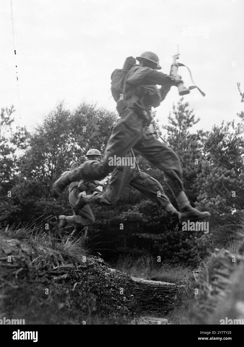 AVEC LES GARDES EN FORMATION, cette série de photos, prises dans un camp dans le sud de l'Angleterre, montre l'entraînement intense par lequel passent ces soldats modernes avant d'être vendus dans les bataillons du Service. Pendant quatre mois, les jeunes gardiens travaillent dur, nageant en équipement complet, escaladant les murs, sautant les fossés et apprenant généralement les subtilités de la guerre moderne. Les photos montrent : les gardiens écossais en parfait alignement prennent un large fossé dans leur foulée pendant l'entraînement. 28 août 1941 Banque D'Images
