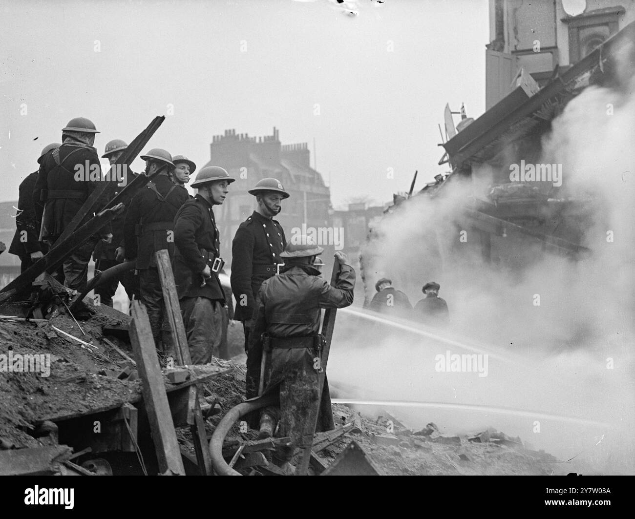 MAISONS DAMAKGED LORS DE RAIDS NOCTURNES SUR DES maisons de LA RÉGION DE LONDRES ont été endommagées par des bombes larguées par des raids allemands lors de raids nocturnes sur la région de Londres. (Walworth Road) photo montre : pompiers auxiliaires jouant les tuyaux sur l'une des maisons enterrées. 9 décembre 1940 Banque D'Images
