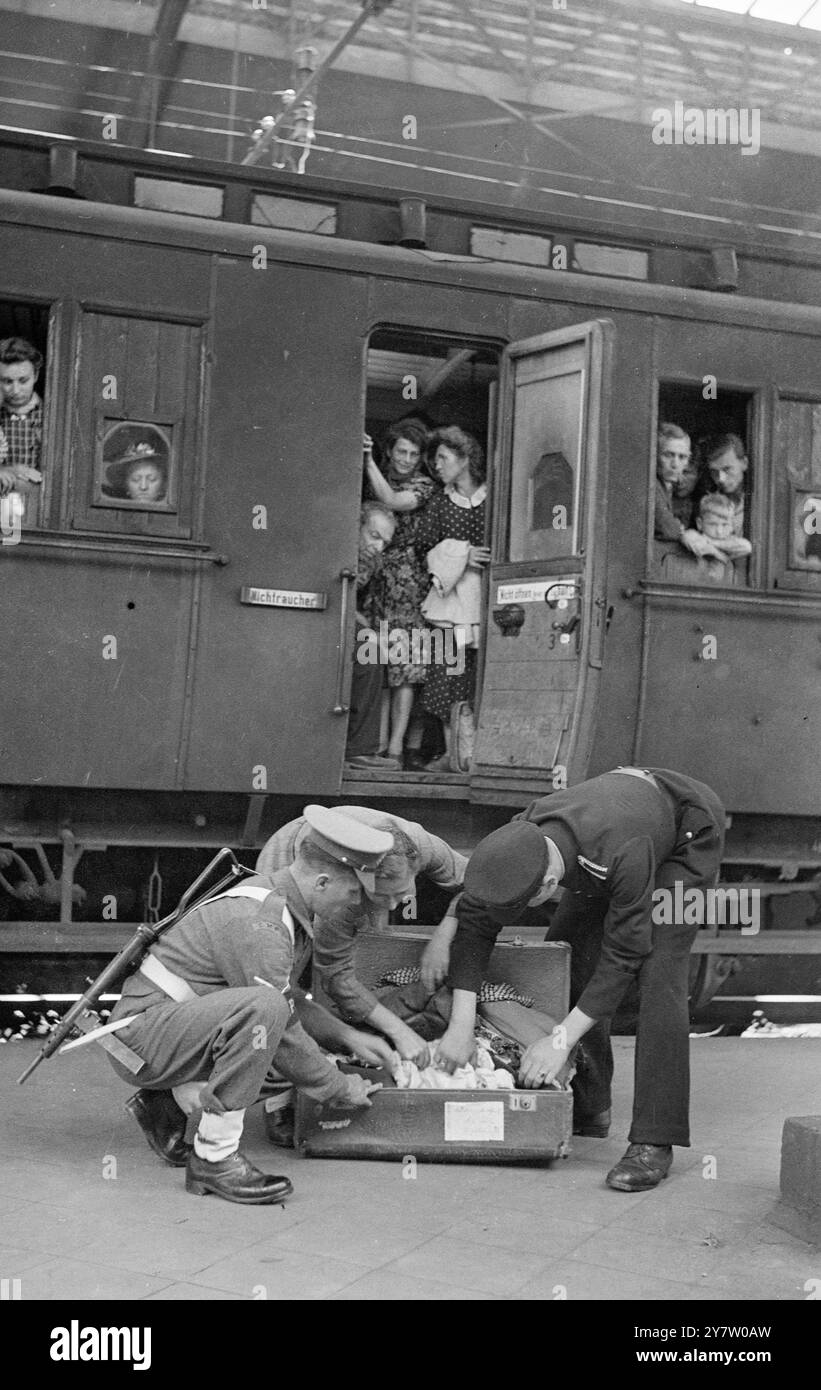 LA POLICE MILITAIRE BRITANNIQUE EN ALLEMAGNE A SAUTÉ SUR DES TRAINS TRANSFRONTALIERS POUR LES OPÉRATEURS DU MARCHÉ NOIR. - - Les trains de voyageurs à destination et en provenance de Hollande et de Belgique sont fréquemment fouillés à la gare de Krefeld, en Allemagne, par la police militaire britannique et la police allemande pour les opérateurs du marché noir et leur stock dans le commerce. - Les petits exploitants qui ont été à quelques kilomètres dans le pays pour troquer des cigarettes et des produits de luxe similaires pour quelques légumes ne sont pas troublés. - Au cours de la recherche montrée sur ces photos, un soldat belge a été pris avec entre 40 et 50 livres de café, d'une valeur d'environ 400 £ sur le noir Banque D'Images