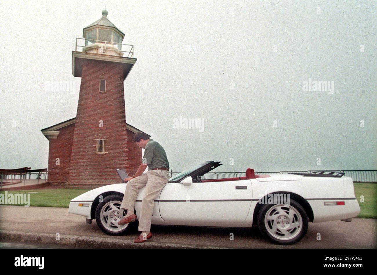 Santa Cruz, Californie : Rick Armillotto est un administrateur système de Thuridion, une société de logiciels de Santa Curz ici il travaille sur un ordinateur portable sur le capot de sa Corvette 1990 près du phare de Santa Cruz. Le phare abrite un musée du surf. Banque D'Images