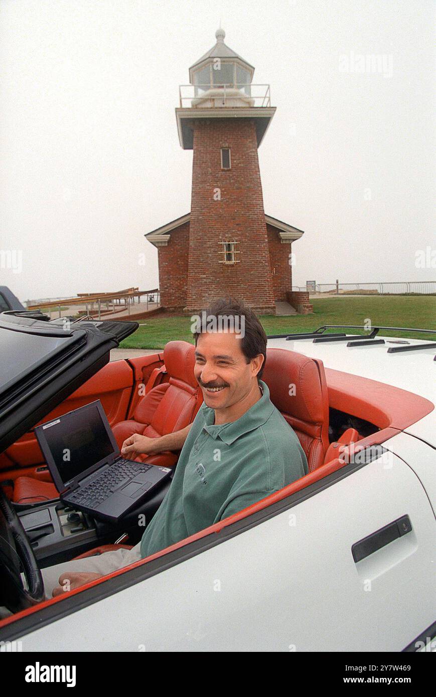 Santa Cruz, Californie : Rick Armillotto est un administrateur système de Thuridion, une société de logiciels de Santa Curz ici il travaille sur un ordinateur portable dans sa Corvette 1990 près du phare de Santa Cruz. Le phare abrite un musée du surf. Banque D'Images