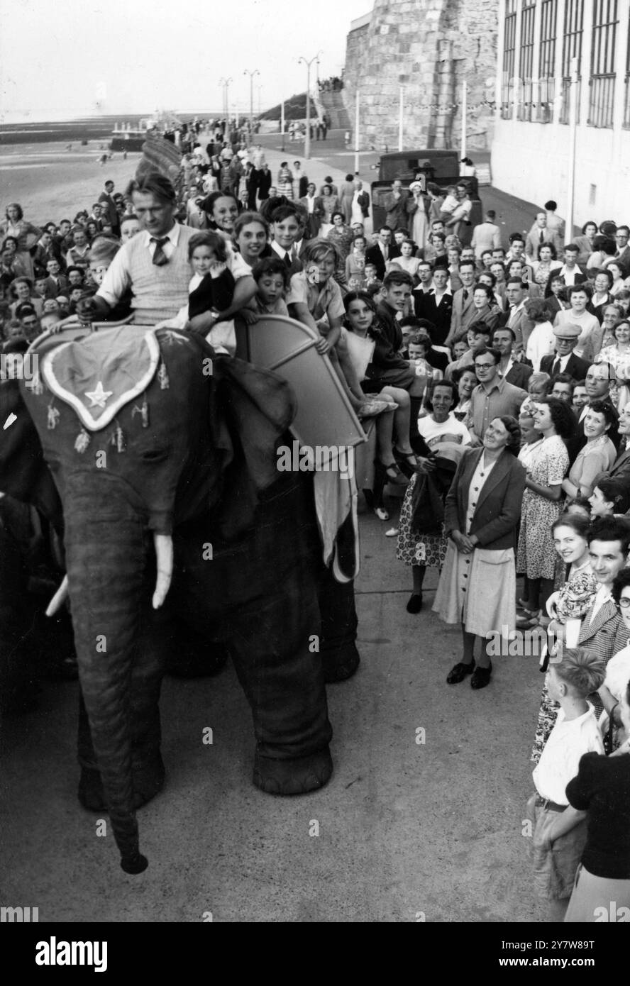 PACHYDERME À ESSENCE RENCONTRE LES FOULES MARGATE 1200 lb éléphant qui est arrivé à Margate hier pour ravir les foules et prendre les enfants pour des promenades n'était pas intéressé par les petits pains et n'a jamais vu la jungle . Jeannie , bien que la plus réaliste à regarder , est purement mécanique , à essence mais peut déplacer son tronc et sa tête et marcher . M. Frank Stuart , l'inventeur , qui a reçu des commandes de répliques de nombreuses régions du monde , a dû demander un permis de conduire pour l'éléphant . L'IMAGE MONTRE:- Jeannie l'éléphant mécanique de 1200 lb fait son chemin à travers les foules Margate avec un Banque D'Images