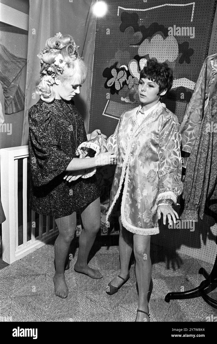 Tout ce dont vous avez besoin est les manches raccourcies cher! Sophie Placidt, 19 ans, de Paris, ne semble pas sûre de l'équipement qu'elle essaie sur l'un des stands du nouveau marché londonien de Kensington. La propriétaire du stand de la boutique, Jackie (vu à droite avec des fleurs dans ses cheveux et un motif sur sa joue) fait la légère modification à une manche, alors qu'elle tente de faire une vente. Le nouveau marché de Kensington a environ 80 stands où tout ce qui va des affiches aux sculptures indiennes peut être acheté, Kensington High Street, Londres, Angleterre.15 septembre 1967 Banque D'Images