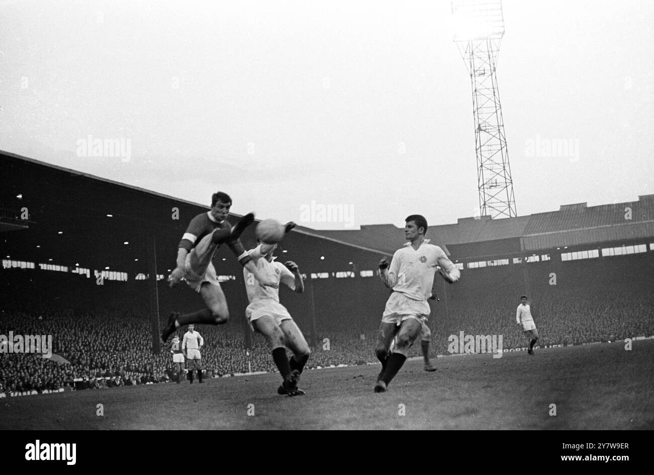 David Herd, joueur de Manchester United, est photographié en train de frapper vers le but du Partizan avec les défenseurs Partizan Davidovic et Rosovic (à droite) en cours d'exécution , lors de la deuxième manche de la demi-finale de la Coupe d'Europe entre Manchester United et le Partizan de Belgrade sur le terrain d'Old Trafford ici ce soir . United a battu Partizan 1-0 après que le gardien tchèque Soskic ait mis le ballon dans son propre but après 73 minutes. Partizan passe maintenant à la finale avec un agrégat victorieux de 2-1 , après avoir battu Manchester United 2-0 dans la première manche . 20 avril 1966 Banque D'Images