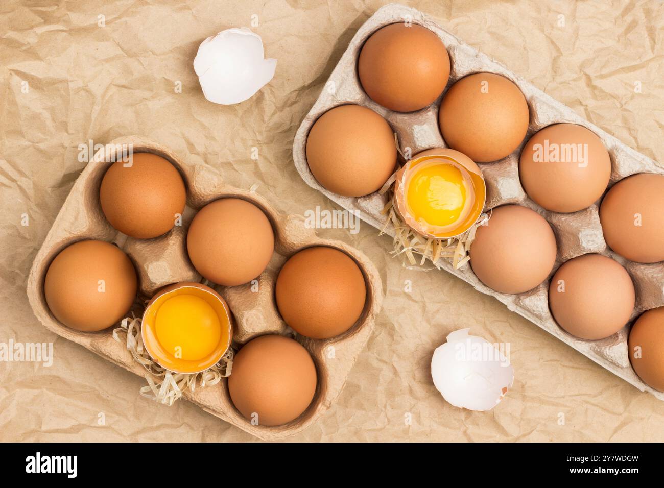 Faire dorer les œufs de poule dans un récipient en carton. Oeuf cassé dans le récipient. Coquille d'oeuf sur table. Fond brun de papier froissé. Pose à plat Banque D'Images