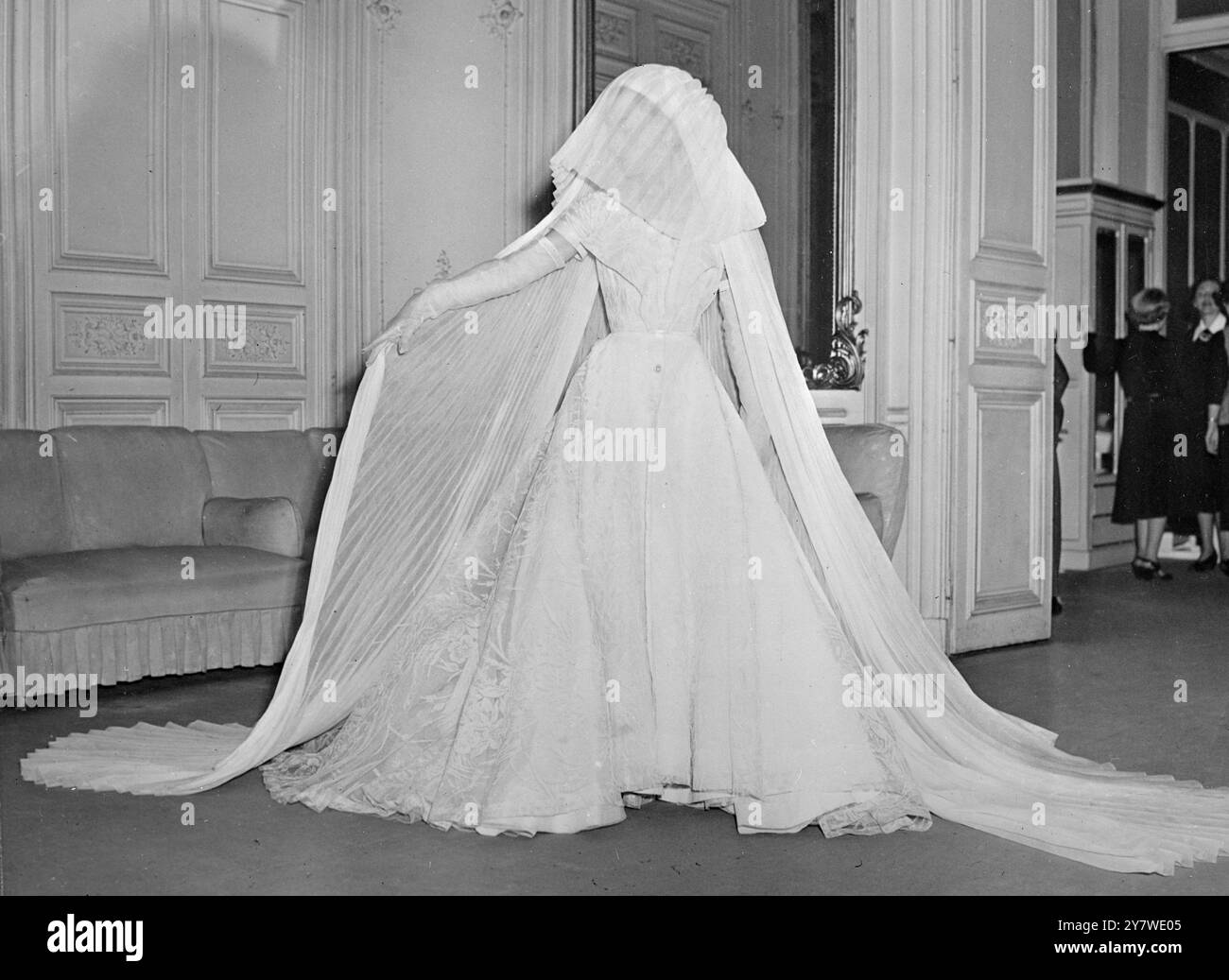 La dernière robe de mariée de Schiaparelli est en tulle brodé blanc avec des manches extrêmement courtes et boutonnée sur le devant. L'ensemble se distingue par ses verges de voile d'organdy plissé blanc drapé comme une coiffe de nonne sur la tête, le modèle porte des gants d'organdy blancs qui rejoignent les manches de la robe. 23 mai 1950 Banque D'Images