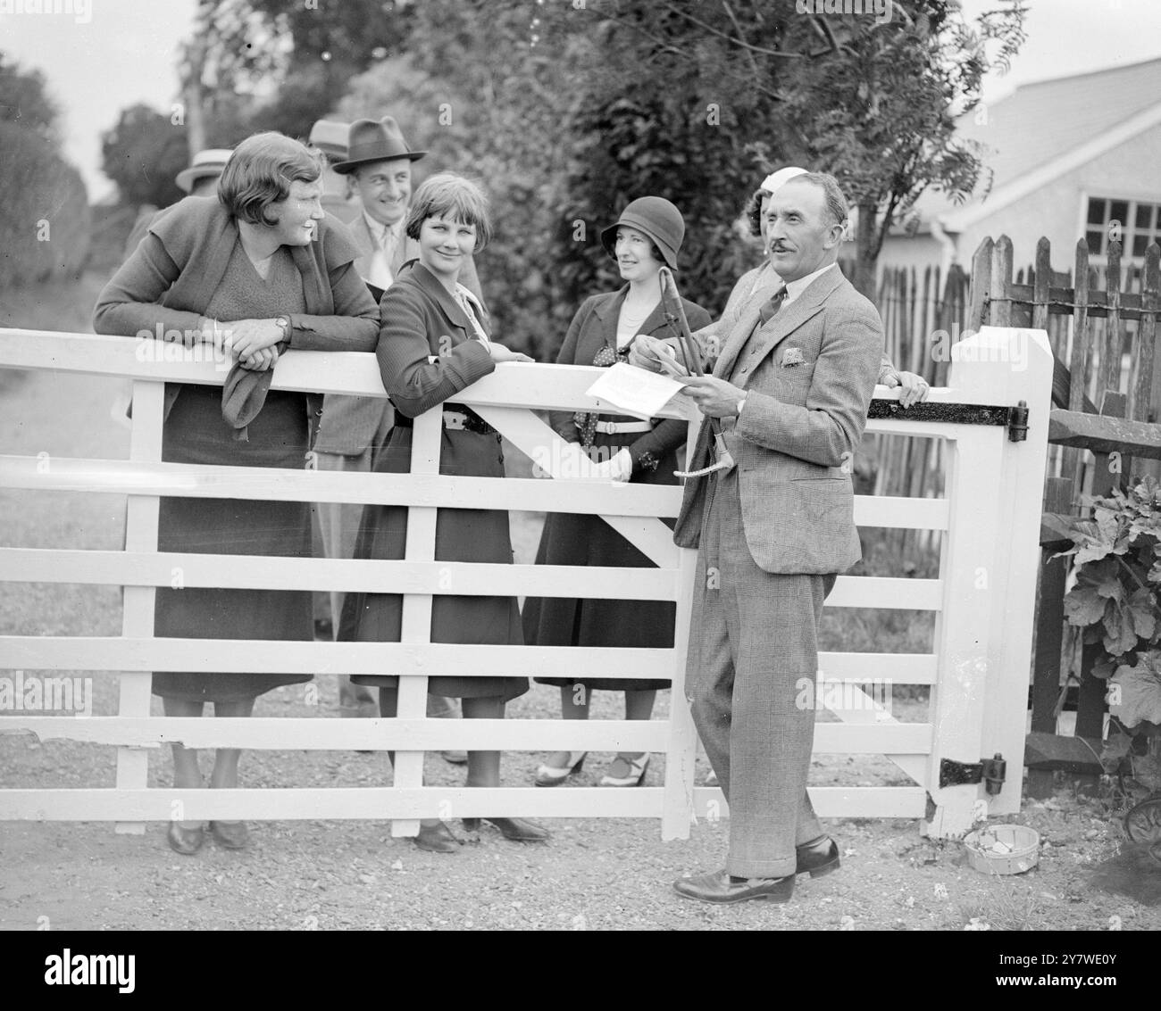 Epsom , Surrey . M. Tom Walls , acteur comique et producteur et entraîneur de chevaux de course , a joué le rôle de ' carrière ' dans une chasse au trésor automobile organisée par Mme Tom Walls en rapport avec une ' fantasie ' tenue au ' Durdans ' au profit de ' l'association Lest we Forget ' et des ' Ashtead Potters ' . Il est vu ici avec sa famille et ses amis. 10 juin 1933 Banque D'Images