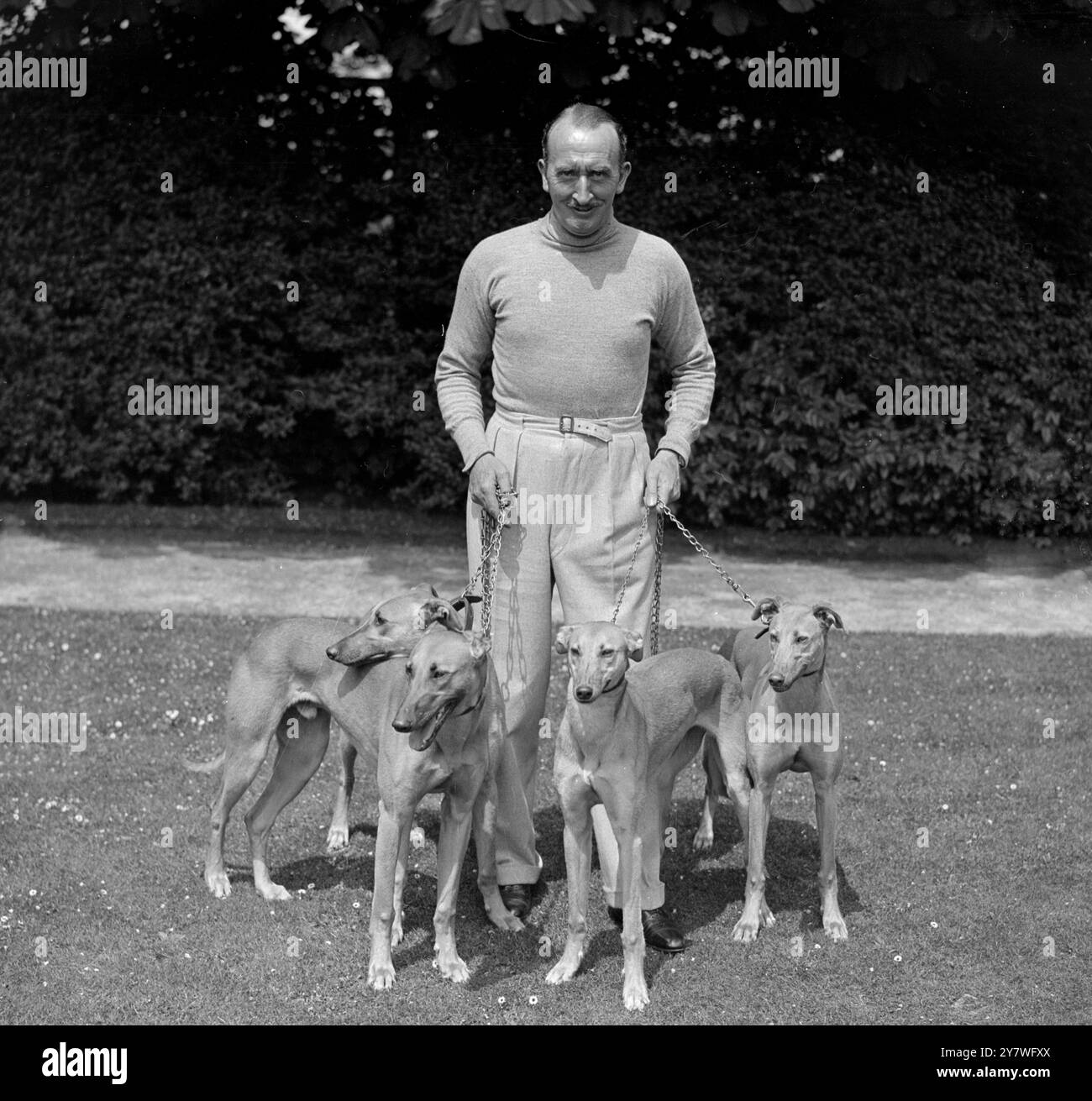 M. Tom Walls , acteur, propriétaire et entraîneur de chevaux de course , avec ses lévriers à son domicile à Ewell , Surrey 1932 Banque D'Images