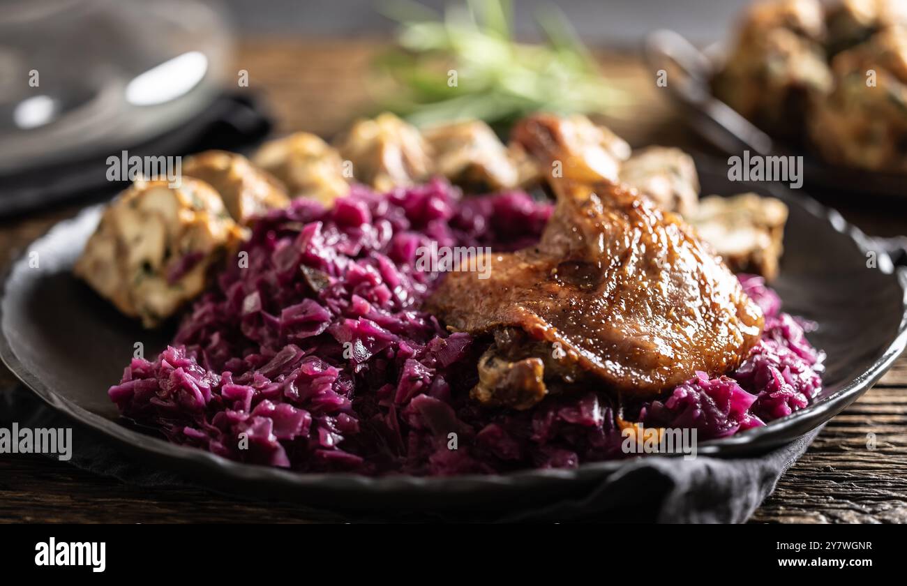 Partie de cuisse de canard rôti boulettes maison chou rouge sur la plaque et le vin rouge sur l'arrière-plan. Banque D'Images