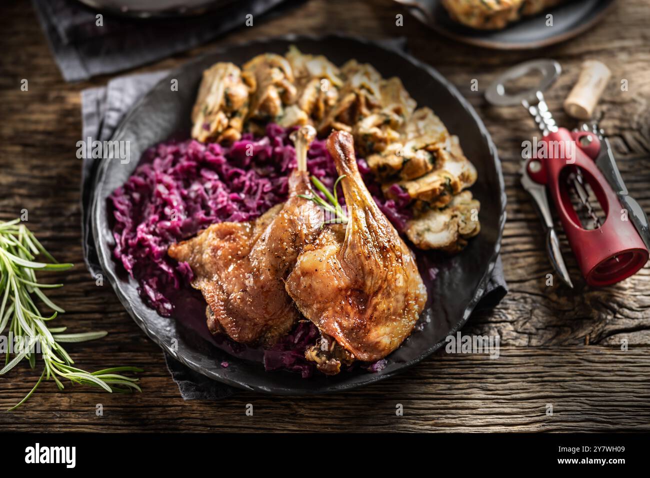 Partie de cuisse de canard rôti boulettes maison chou rouge sur la plaque et le vin rouge sur l'arrière-plan. Banque D'Images