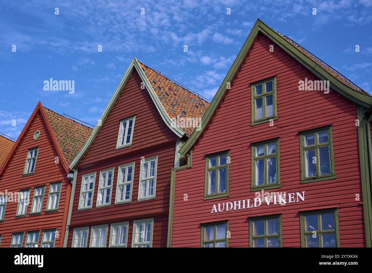 Maisons traditionnelles en bois rouge sous un ciel bleu avec des toits inclinés et de multiples fenêtres dans une vieille ville ensoleillée, Bryggen, Bergen, Vestland, Norvège, Europe Banque D'Images