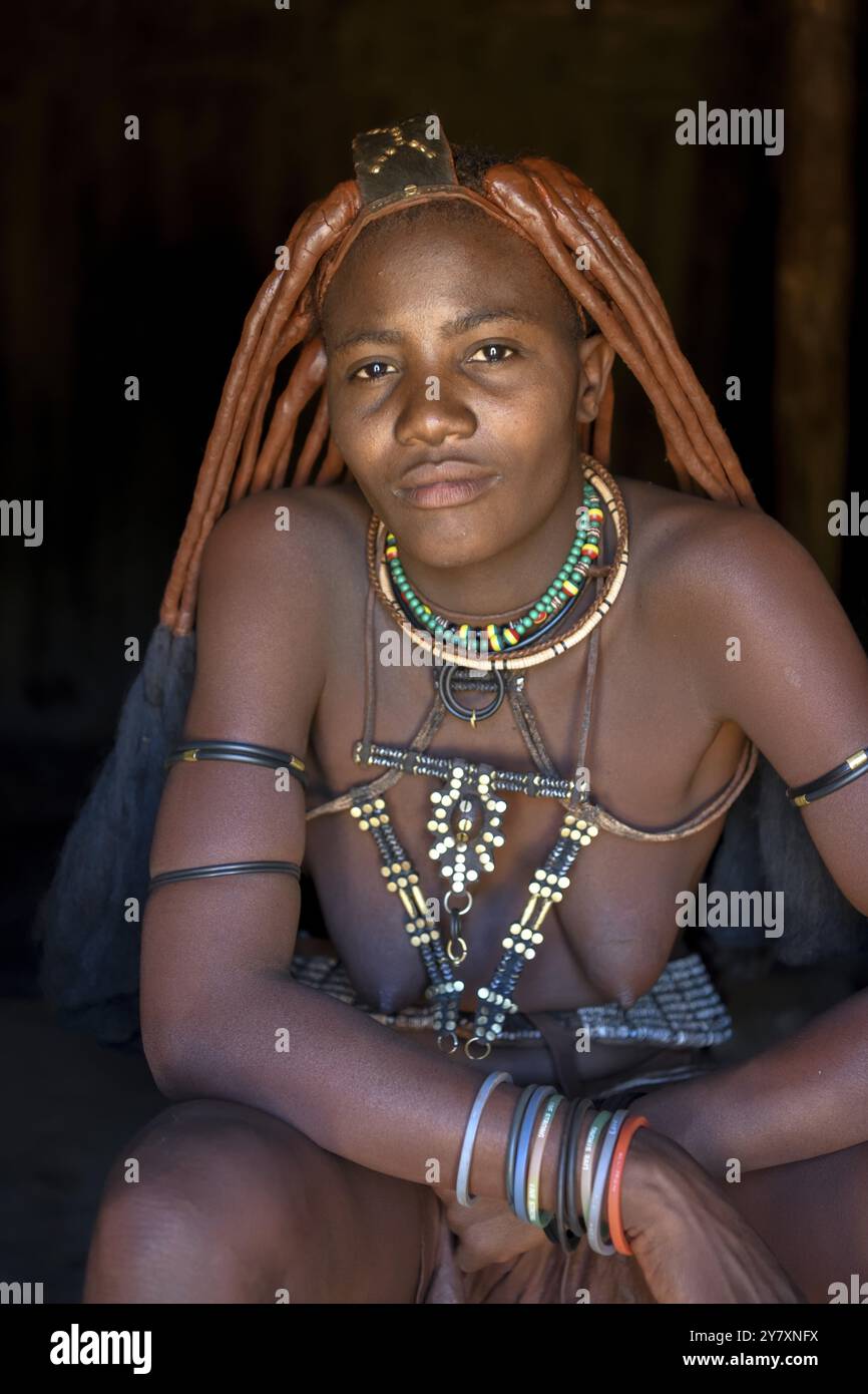 Jeune femme himba dans sa cabane, Ohandungu, région de Kunene, Kaokoveld, Namibie, Afrique Banque D'Images