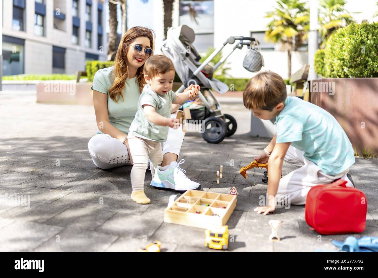 Photo pleine longueur d'une femme heureuse et de fils jouant avec des jouets dans un espace urbain Banque D'Images