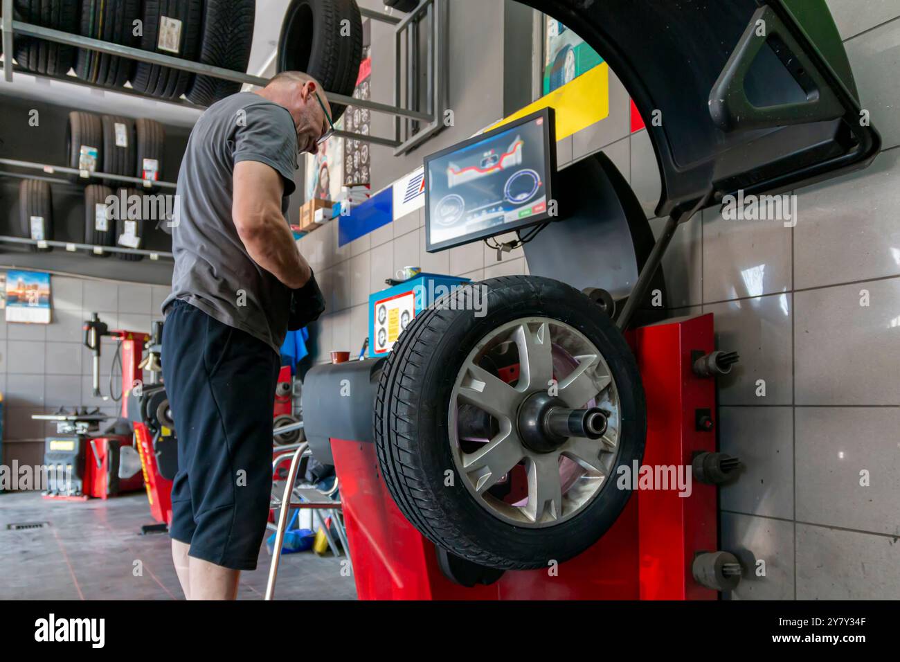 Entretien des roues de voiture. Réparation et remplacement des pneus par des experts à un point de vulcanisation fiable avec un service fiable. Homme technique équilibrant les pneus, mainte Banque D'Images