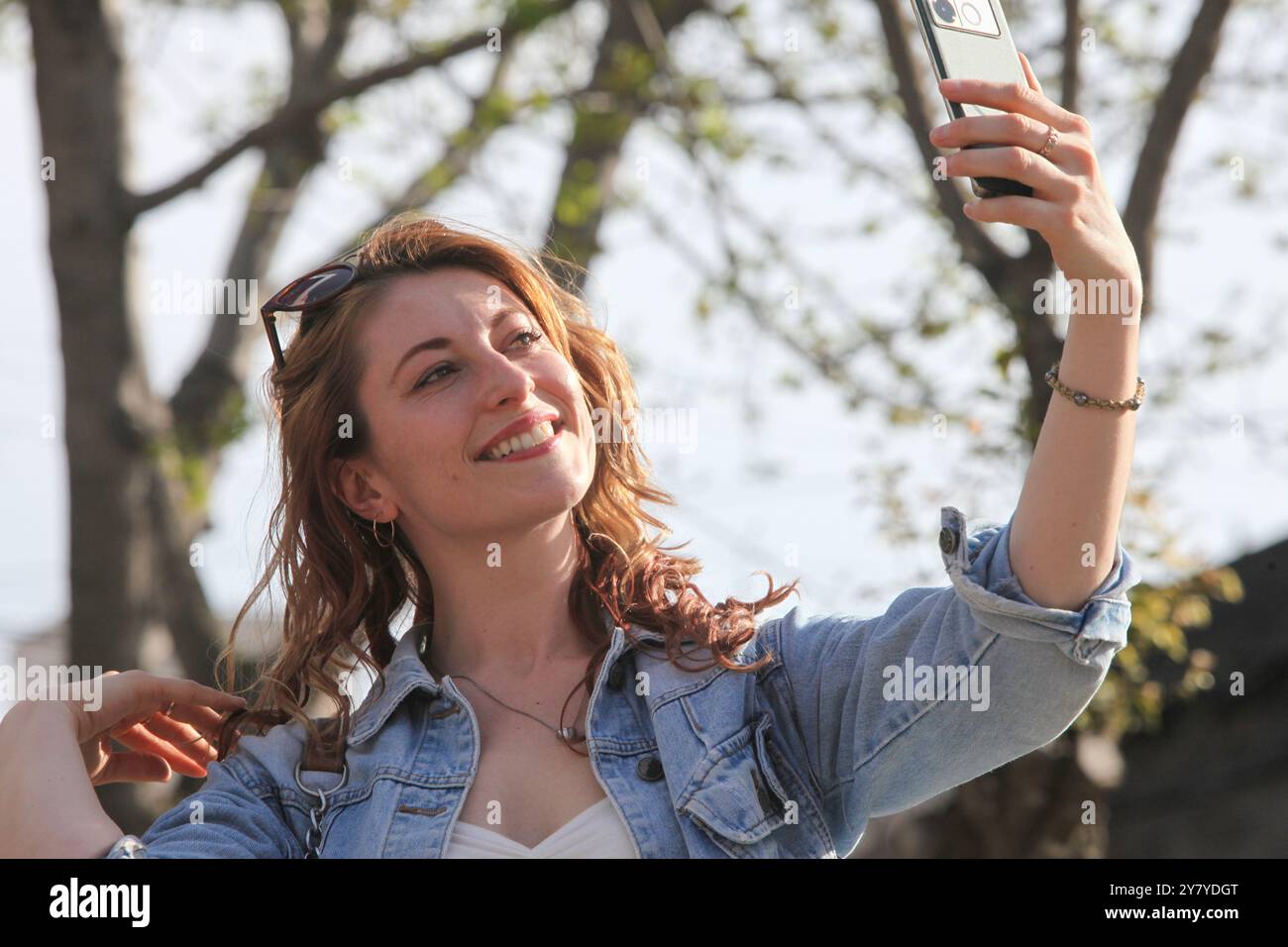 portrait d'une jolie femme joyeuse prenant une photo avec un téléphone portable dans la rue Banque D'Images