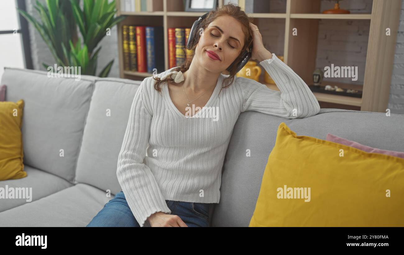 Une jeune femme détendue aime la musique avec des écouteurs dans un salon confortable avec un décor élégant Banque D'Images