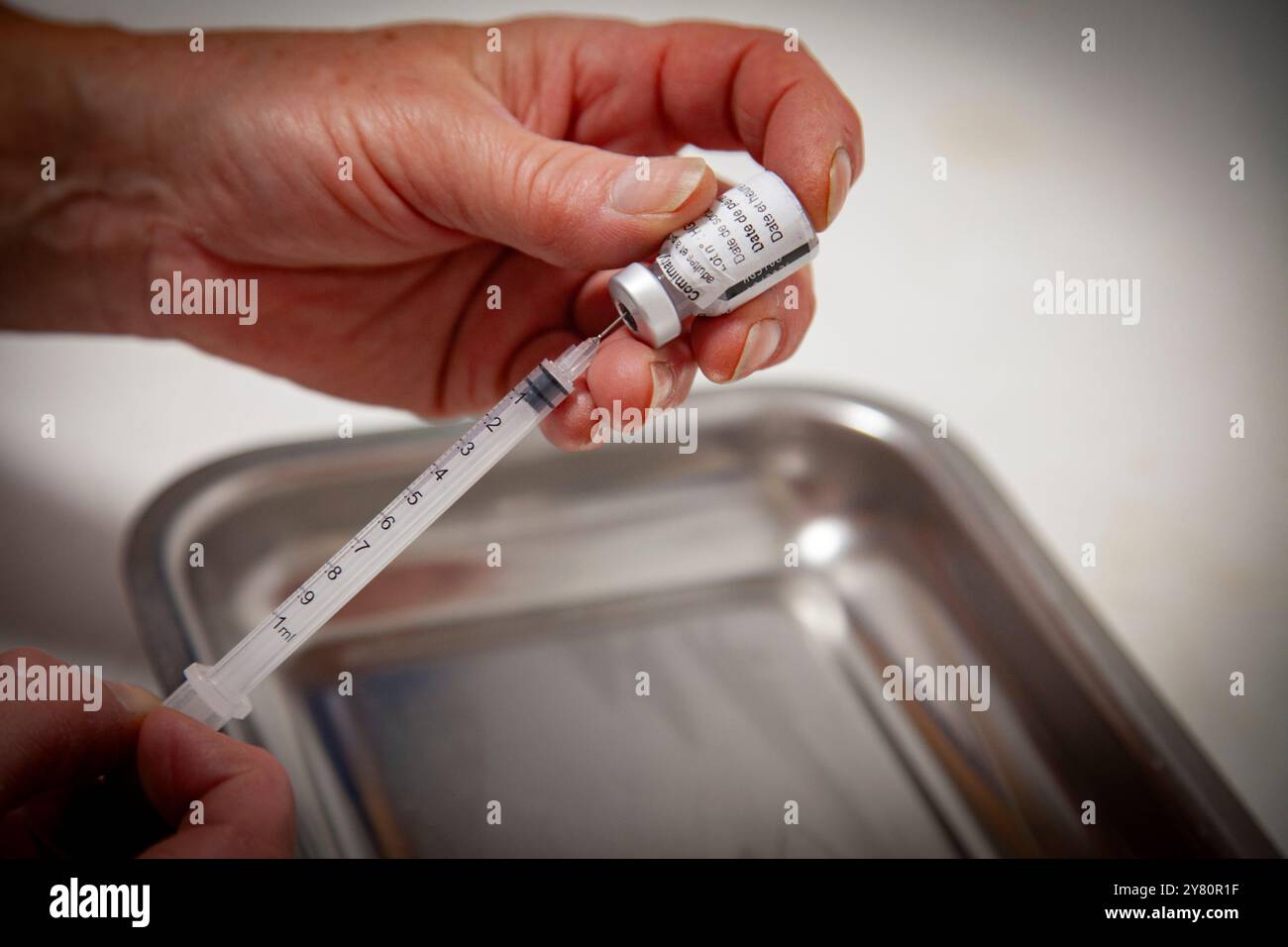 Vaccination contre le Covid-19 en pharmacie : un pharmacien prépare des doses de vaccins contre la grippe saisonnière et le covid19 pour la journée, un flacon d’ARNm de Comirnaty vac Banque D'Images