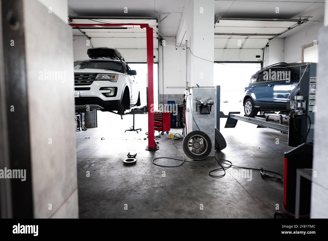 Intérieur d'un atelier de réparation automobile moderne mettant en vedette des véhicules sur des ascenseurs hydrauliques. Le garage spacieux est équipé d'outils et de machines pour la voiture maintena Banque D'Images