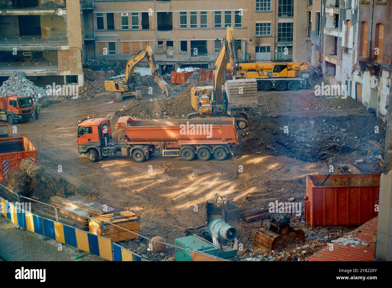 Chantier de construction avec excavatrices et camions au milieu des débris de démolition, vu de dessus. Banque D'Images