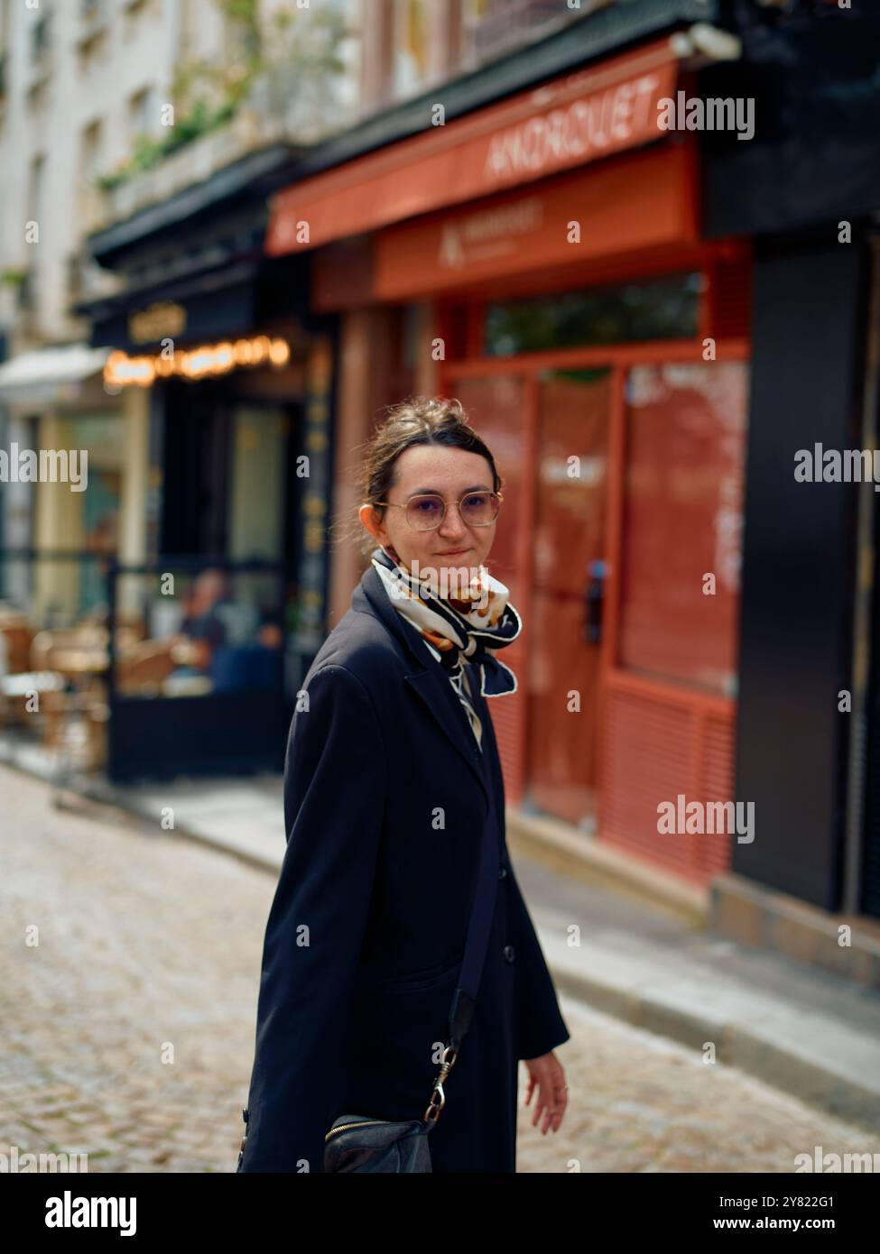 Femme marchant dans une rue de la ville avec un café en arrière-plan. Banque D'Images