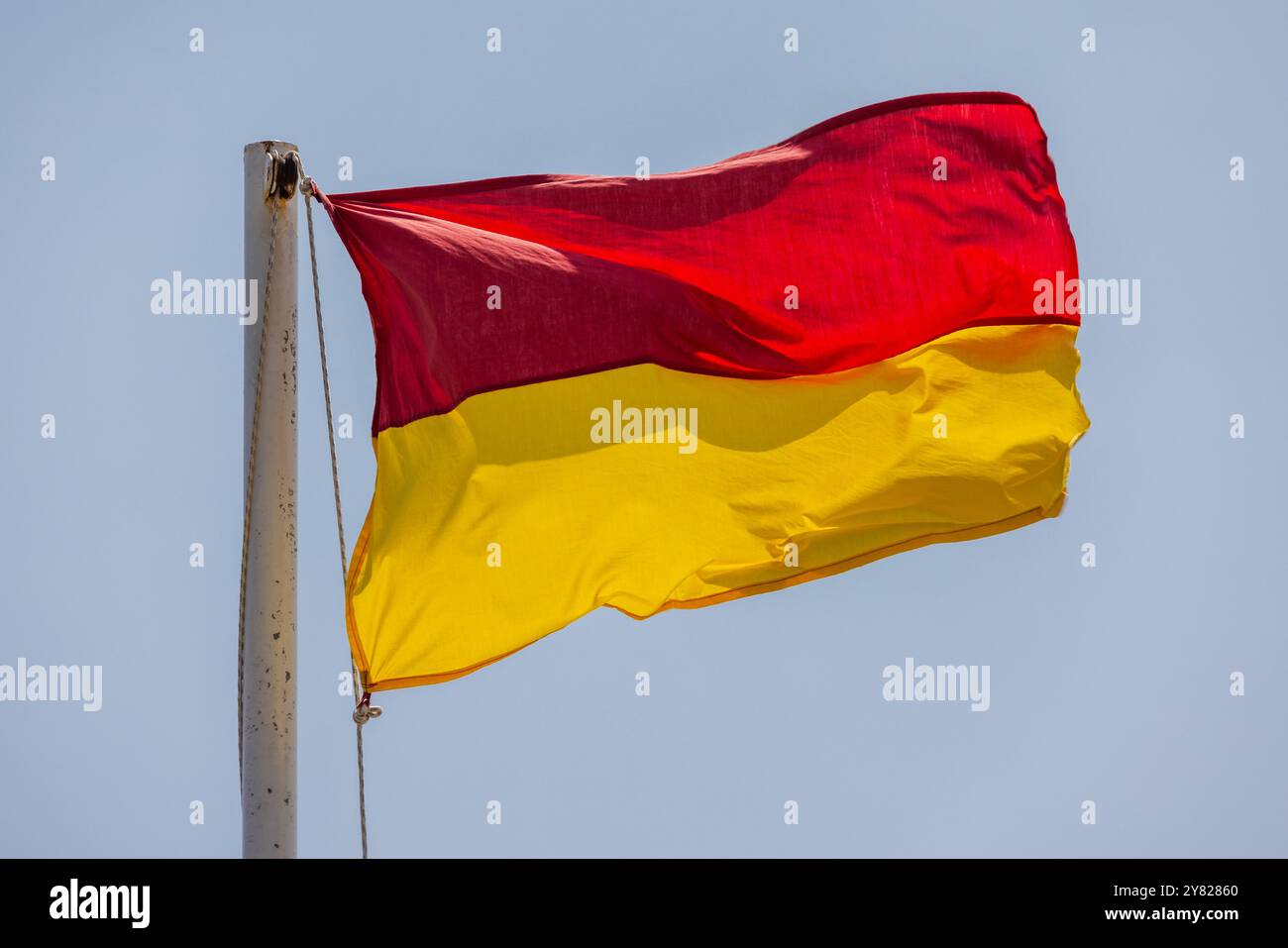 Drapeau de plage rouge et jaune d'avertissement est sous fond de ciel bleu Banque D'Images Drapeau de plage rouge et jaune d'avertissement est sous fond de ciel bleu Banque D'Images