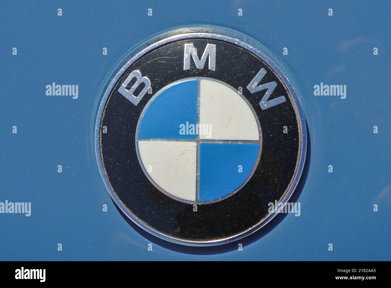 Gros plan d'un logo bmw sur une surface bleue, brillant au soleil Banque D'Images