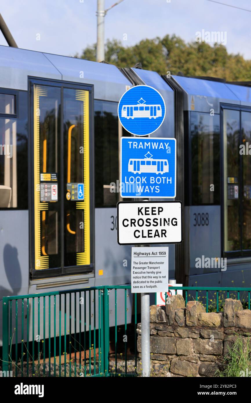 Panneau d'avertissement bleu et blanc de tramway au tramway de tramway avec tramway de réseau d'abeille passant en arrière-plan à radcliffe Greater manchester uk Banque D'Images