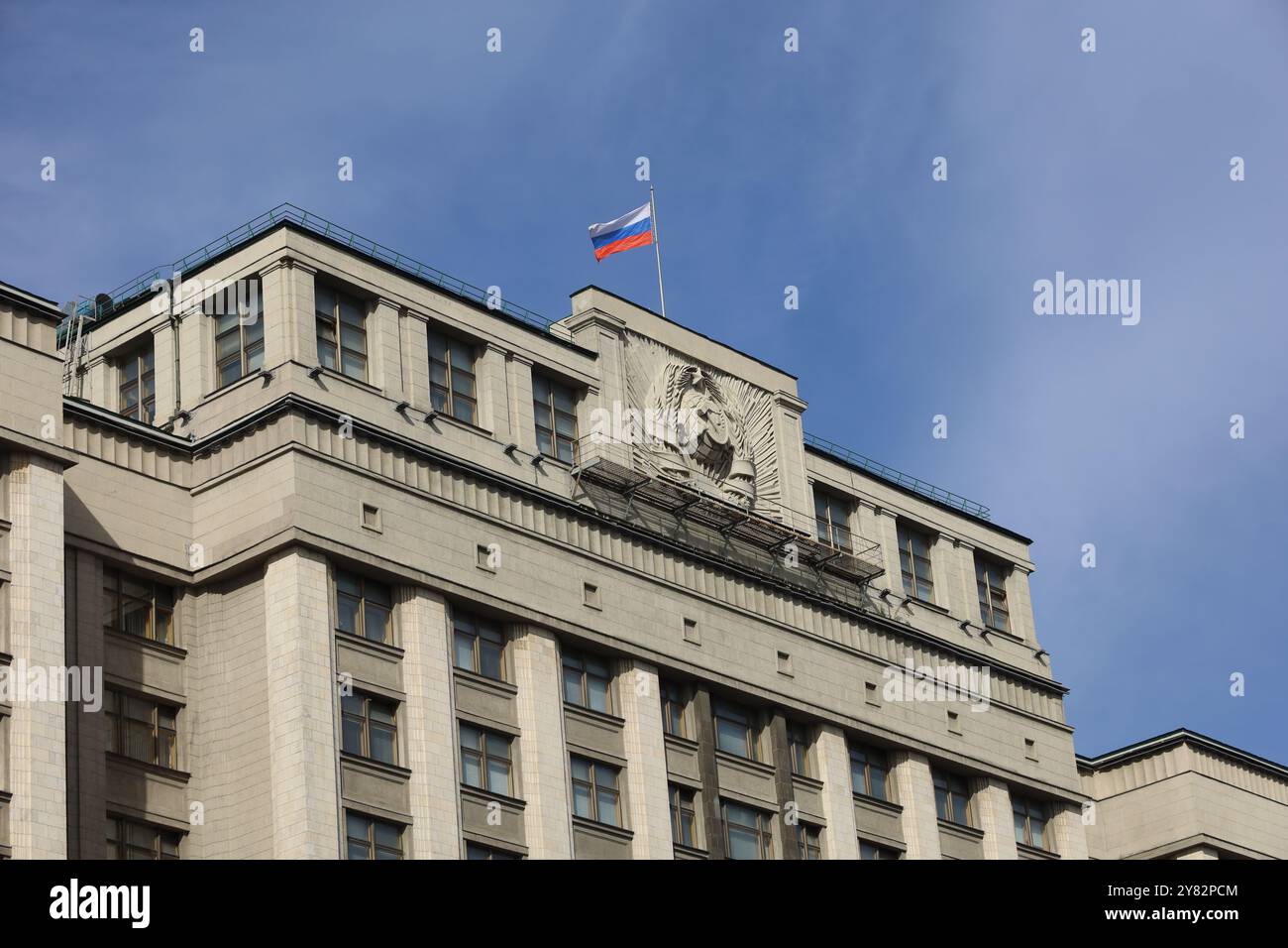 Drapeau russe sur le bâtiment du parlement à Moscou contre le ciel bleu. Façade de Douma d'état de la Russie soviétique avec des armoiries, de l'autorité russe Banque D'Images