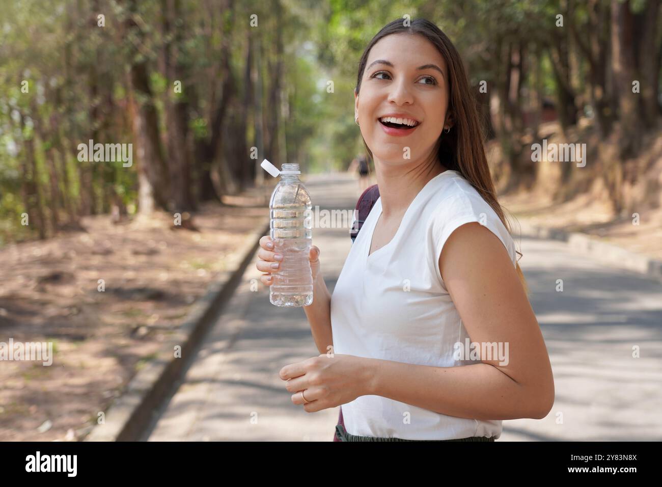 Bouchon attaché sur la bouteille en plastique. Portrait d'une jeune femme tenant une bouteille en plastique d'eau avec un nouveau bouchon attaché pour encourager le recyclage, dans le cadre du Banque D'Images