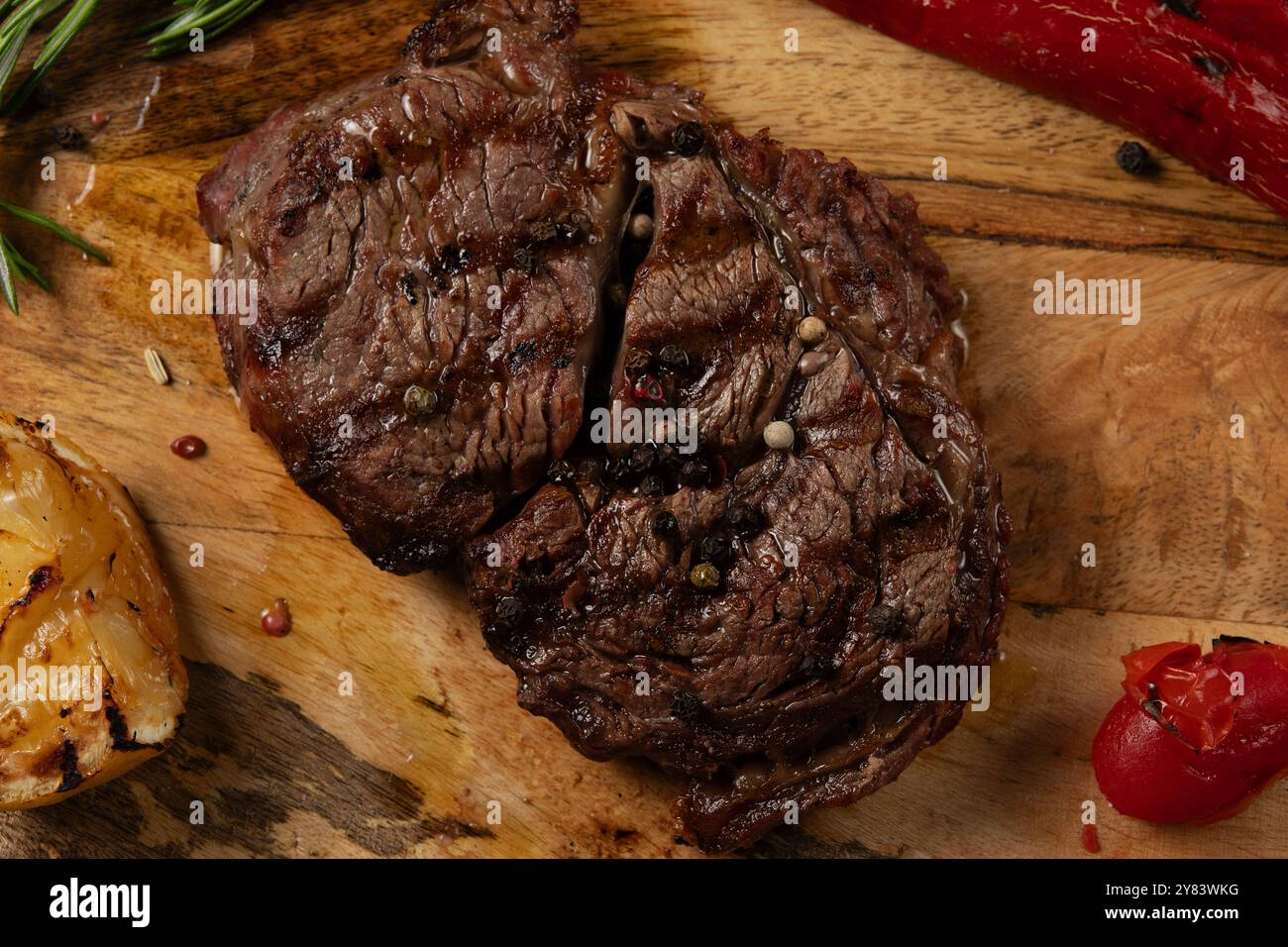 Gros plan grillé Rib Eye Black Angus servi avec du poivre et des herbes sur fond de bois. Banque D'Images