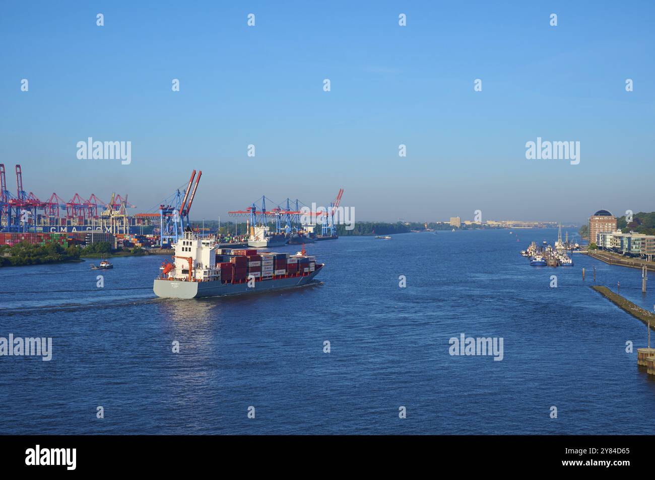 Un cargo sur l'Elbe entouré de grues portuaires et de bâtiments sous un ciel bleu clair, Hambourg, Allemagne, Europe Banque D'Images