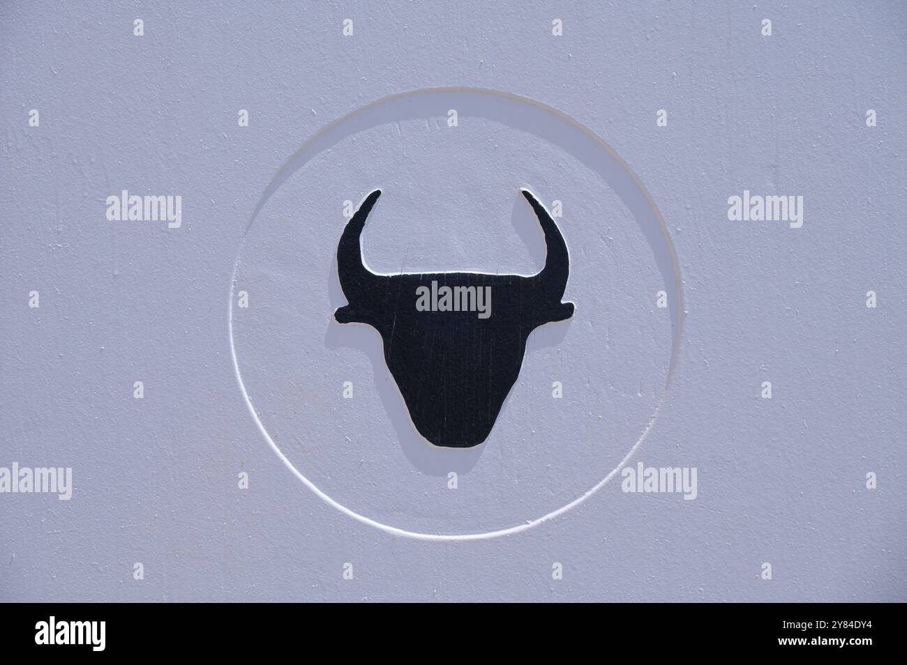 Image minimaliste d'une tête de taureau noir sur fond blanc, arène de tauromachie, Saintes-Maries-de-la-mer, Camargue, France, Europe Banque D'Images