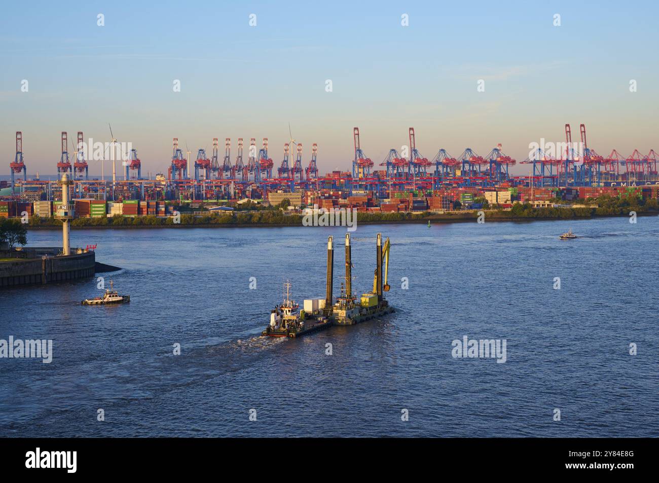 Paysage urbain d'un port sur l'Elbe, avec de nombreuses grues, conteneurs, navires et éoliennes sous un ciel bleu en lumière tamisée, lever du soleil, Hambourg, Allemagne Banque D'Images