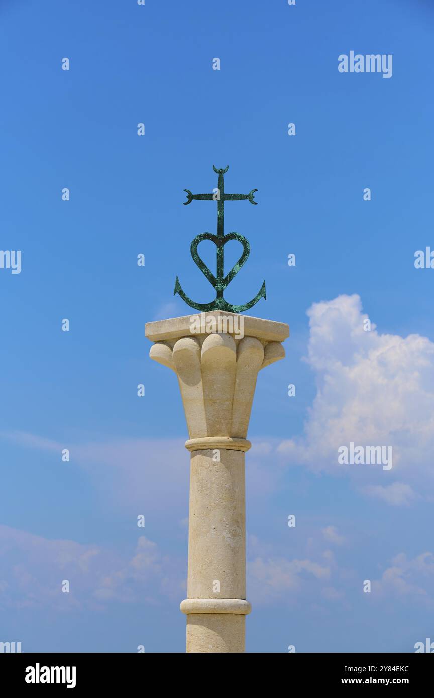 Colonne de pierre avec la croix décorative de la Camargue, devant un ciel bleu avec nuages, été, Saintes-Maries-de-la-mer, Camargue, France, Europe Banque D'Images