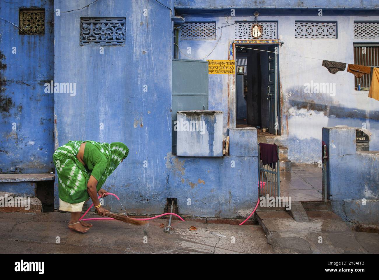 Femme en sari vert, tuyau d'eau rose, maison peinte en bleu, Bundi, Rajasthan, Inde, Asie Banque D'Images