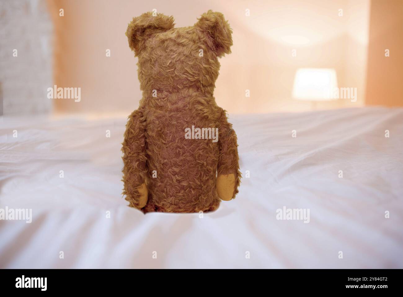 Ours en peluche assis sur un lit, image symbolique enfance solitaire Banque D'Images