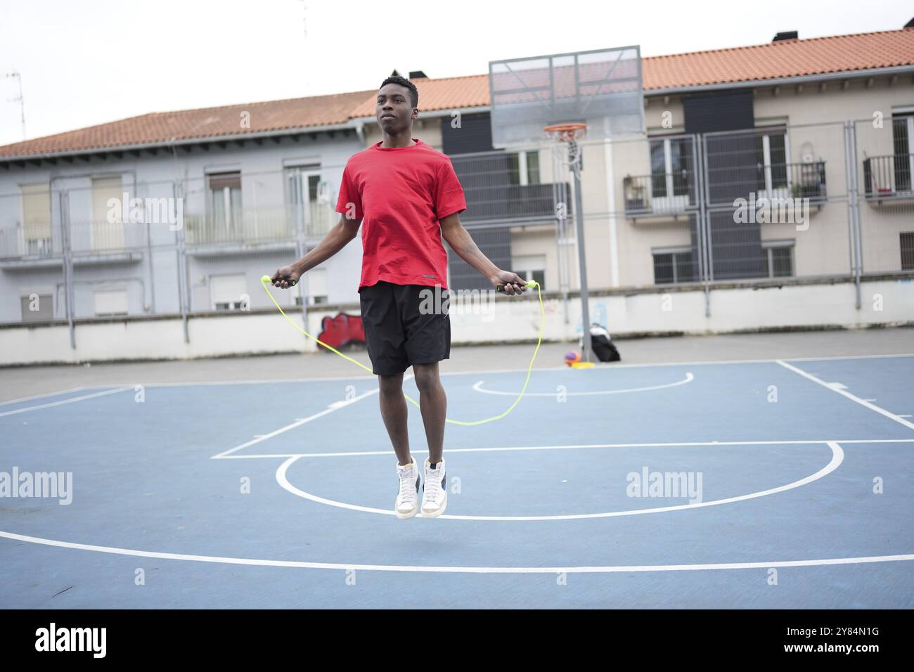 Un jeune homme d'ascendance africaine exerçant à la corde à sauter dans un terrain de basket-ball extérieur public Banque D'Images