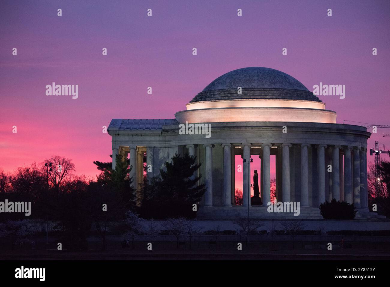 Jefferson Memorial Silhouette Sunrise Washington DC // WASHINGTON DC — le Jefferson Memorial est dessiné sur un ciel rose vif avant l'aube dans cette vue du côté ouest du monument. La statue de Thomas Jefferson se tient bien en évidence au centre du cadre, créant une silhouette spectaculaire dans la structure en dôme du mémorial néoclassique. Achevé en 1943, le mémorial honore le troisième président de l'Amérique et l'auteur principal de la Déclaration d'indépendance. Le mémorial, conçu par l'architecte John Russell Pope, se trouve le long du Tidal Basin dans le parc West Potomac. Les teintes roses de Banque D'Images
